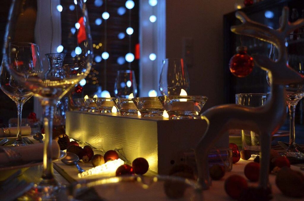 a Christmas themed dinner table setting with Christmas decorations and fairy lights