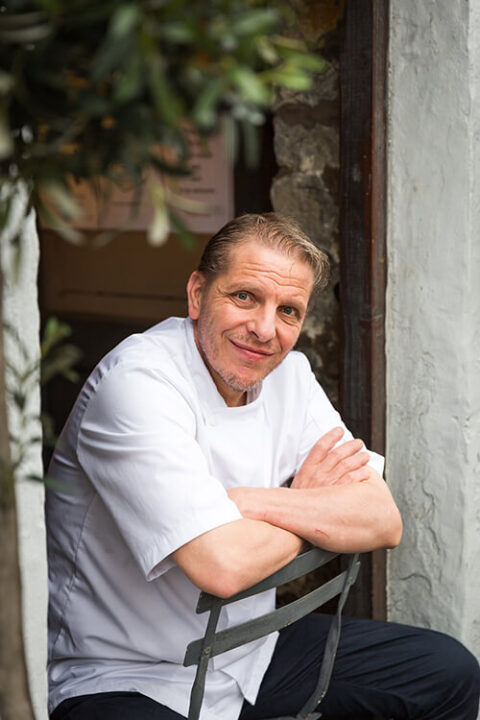 chef patron at La Locanda, Maurizio Bocchi sititng on a chair in the doorway of his Lancashire based Italian restaurant
