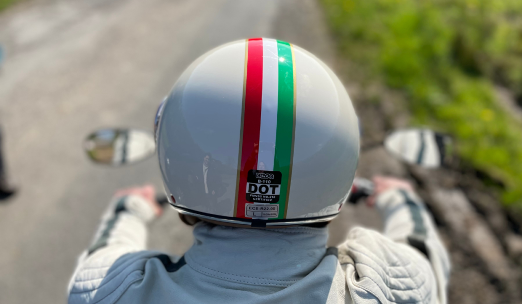 top down view of a motorcyclist riding a motorbike wearing a white helmet with the colours of the Italian running down the centre.