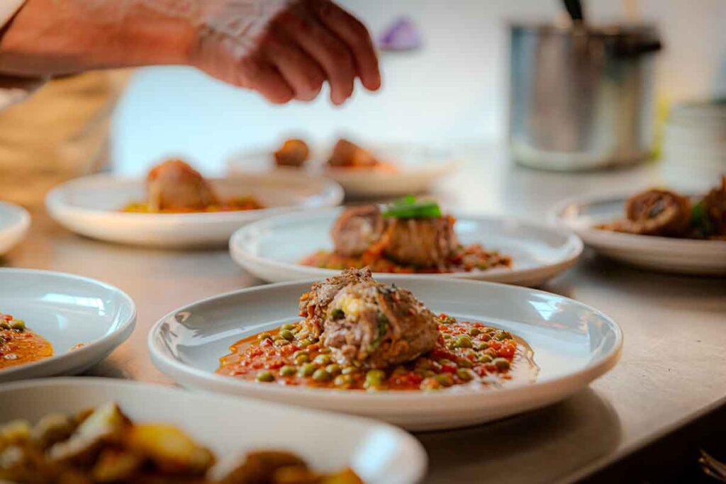 Chef seasoning a plate of freshly prepared Italian food at La Locanda.